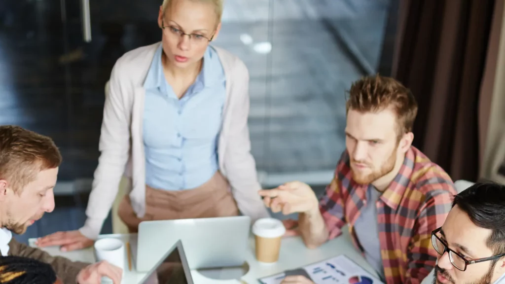 Team di professionisti riuniti attorno a un tavolo con laptop e tablet durante una riunione di lavoro